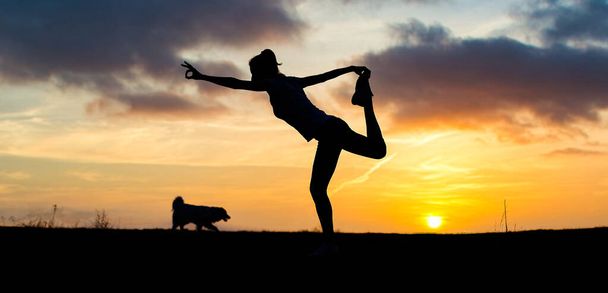 woman in a balancing pose at sunset yoga outdoors - Photo, Image