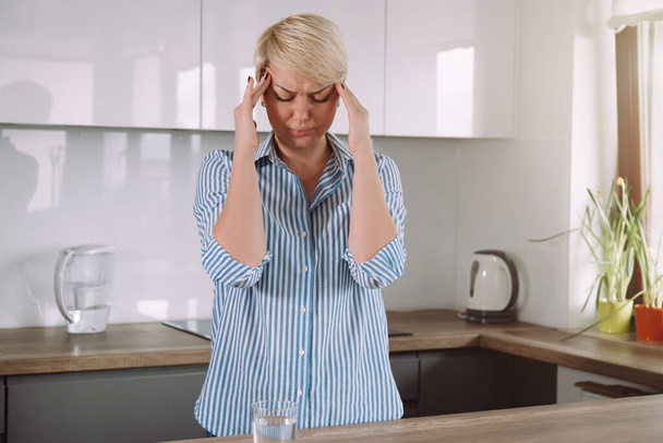 Женщина, держащая голову руками и страдающая от мигрени или головной боли, стресса или депрессии. - Фото, изображение