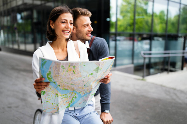 Couple, travel, dating and tourism concept. Happy smiling woman and man in love walking with map in the city - Фото, зображення