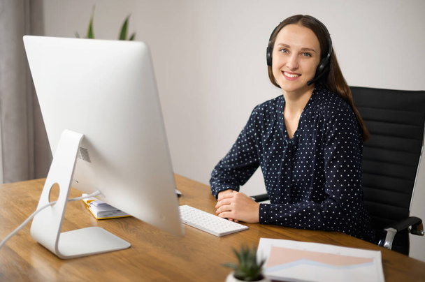 Woman wearing headset works at the office - Foto, Imagen