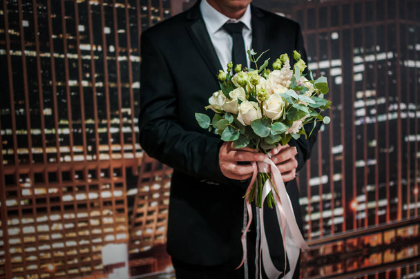 Bouquet with flowers in the hands of a man. The bride's bouquet in the hands of the groom - Foto, afbeelding