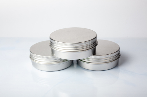 Tres tarros de metal de crema sobre fondo blanco. Maceta de aluminio para productos cosméticos naturales. Cuidado de la piel - Foto, Imagen