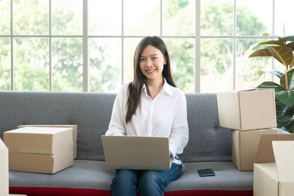 Happy young Asian woman entrepreneur, Smile for sales success after checking order from online shopping store in laptop at home office, Concept of merchant business online and eCommerce - Valokuva, kuva