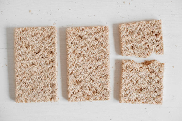 Τραγανό ψωμί σίκαλης σε λευκό ξύλινο φόντο. Στο πάνω μέρος. Αντιγραφή, κενό χώρο για κείμενο. - Φωτογραφία, εικόνα