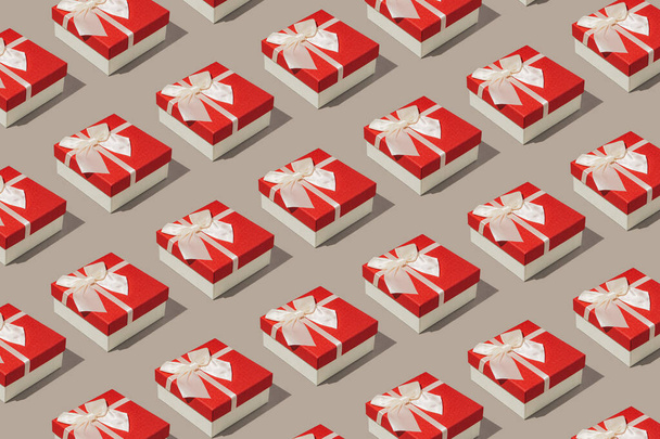 Patrón creativo hecho con cajas de regalo rojas con arcos blancos sobre fondo pastel. Concepto de regalo de Navidad o cumpleaños. Estilo mínimo. - Foto, imagen