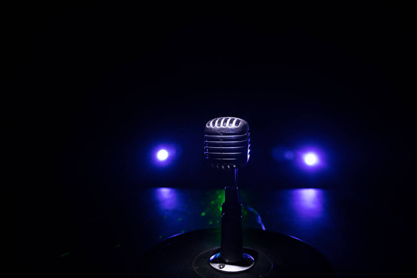 Retro style microphone on background with backlight. Vintage silver Microphone for sound, music, karaoke. Speech broadcast equipment. Live pop, rock musical performance. Selective focus - Photo, Image