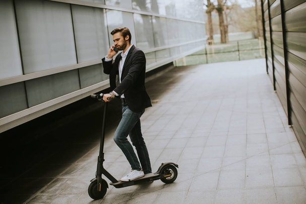 Handsome young businessman using mobile phone  on electric scooter - Φωτογραφία, εικόνα
