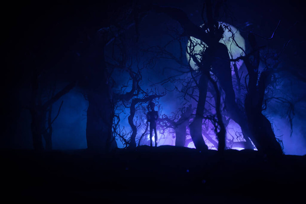 αιμοδιψή ζόμπι επιτίθενται στην ιδέα. Σιλουέτα με τρομακτικά ζόμπι που περπατούν στο νεκρό δάσος τη νύχτα. Δημιουργική διακόσμηση τραπεζιού. Επιλεκτική εστίαση - Φωτογραφία, εικόνα