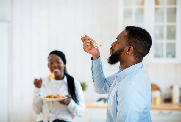 Lezzetli yemek. Aç Afrikalı Amerikalı Adam Mutfakta Uzun Spagetti Höpürdetiyor - Fotoğraf, Görsel