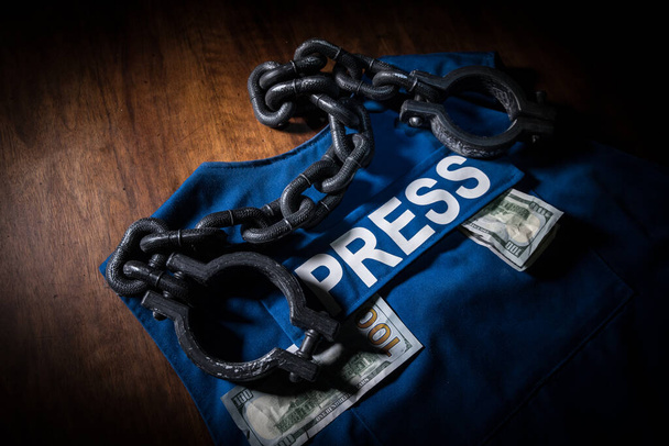 Media Journalism fake news concept. Blue journalist (press) vest in dark with backlight and fog. Dirty money on journalist vest. Selective focus - Photo, Image