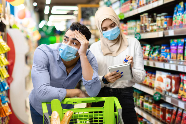 不幸なイスラム教徒のカップルスーパーマーケットで食料品の買い物をする価格を計算する - 写真・画像