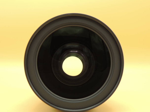 La lente è di 24-70mm 2,8 su fondo giallo. Macro. Un obiettivo della fotocamera. - Foto, immagini