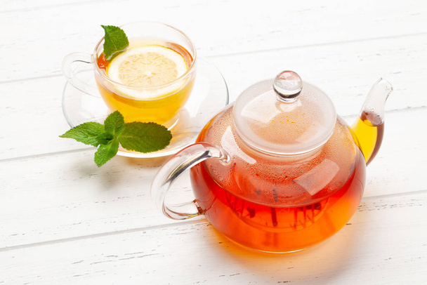 Τσάι με μέντα και λεμόνι. φλιτζάνι τσάι και τσαγιέρα σε ξύλινο τραπέζι - Φωτογραφία, εικόνα