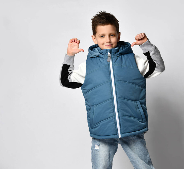 smiling teenager in a quilted or down jacket vest, ready to spend winter holidays and vacations in comfort and warmth, presenting the product, copy space - Foto, Imagem