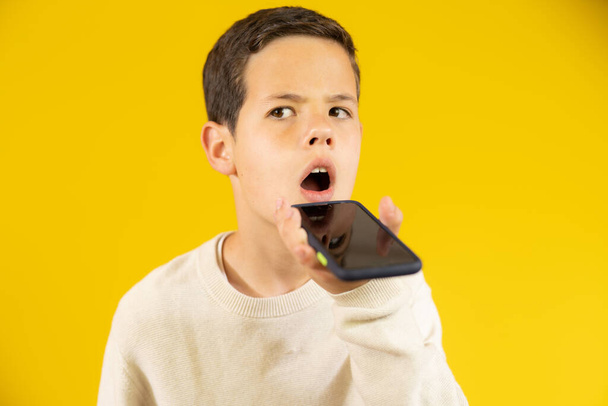 Cute boy mówi przez telefon komórkowy izolowane na żółtym tle. - Zdjęcie, obraz