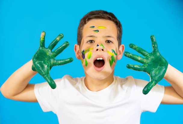 Cute boy with finger paint isolated over blue background. - Fotoğraf, Görsel