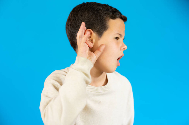 Little child making listening gesture isolated over blue background. - Foto, immagini