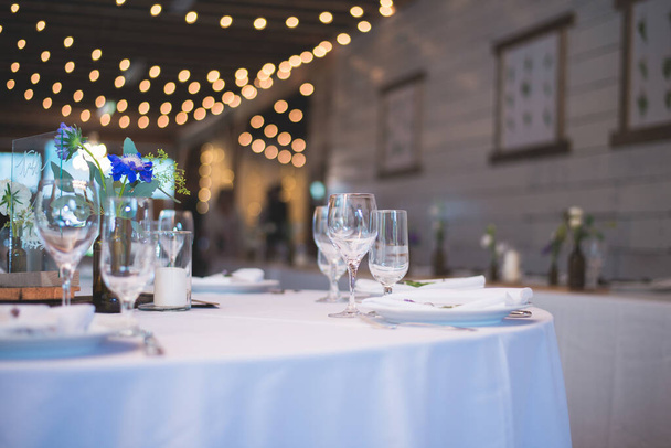 A closeup shot of a wedding table covered with a white tablecloth and utensil - Foto, imagen