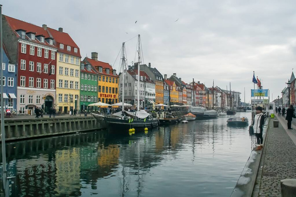 Kopenhagen, Dänemark; 02 14 2016. Nyhavn, berühmte Straße neben den Kanälen von Kopenhagen. Die farbenfrohen Fassaden der Gebäude neben den Booten, die an der Seebrücke anlegen, bilden eine eigenartige Landschaft. - Foto, Bild