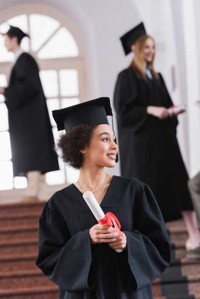 Alegre estudiante afroamericano con diploma en la universidad durante la graduación  - Foto, imagen