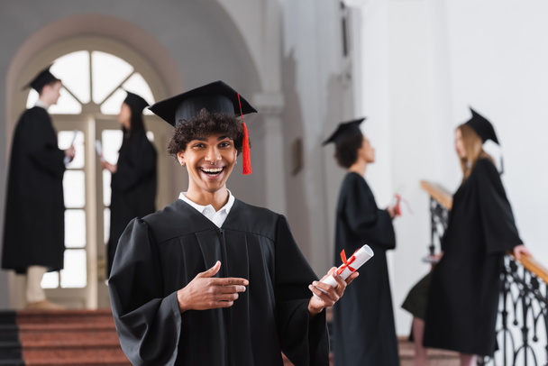 Excited african american bachelor pointing at diploma  - Photo, Image