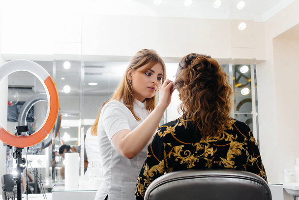 In a beautiful, modern beauty salon, a professional makeup stylist makes makeup for a young girl. Beauty, and fashion - Фото, зображення