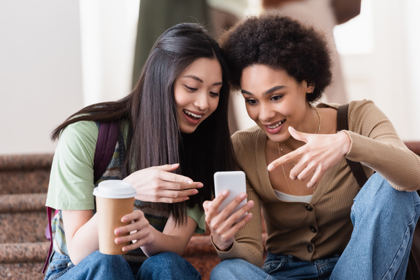 Usmívající se multietnické studenty s kávou jít pomocí mobilního telefonu  - Fotografie, Obrázek