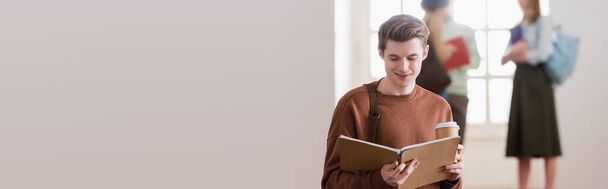 Smiling student with paper cup looking at notebook in university, banner  - Photo, Image