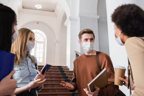 Multiethnic students in protective masks talking in university  - Foto, Imagen
