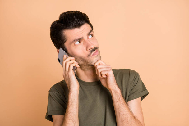 Photo of young thoughtful minded serious man look copyspace talk on phone thinking isolated on beige color background - Фото, зображення