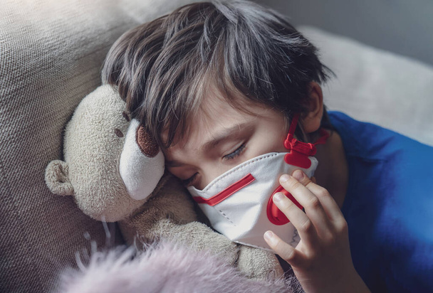 Мальчик устал от кашля груди носить медицинскую маску для защиты pm2.5, ребенок засыпает во время игры с игрушкой, ребенок остаться дома для защиты ковид, вспышки гриппа и защиты от болезней  - Фото, изображение