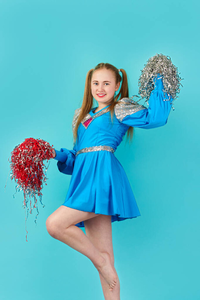 young cheerful girl cheerleader. turquoise background - 写真・画像