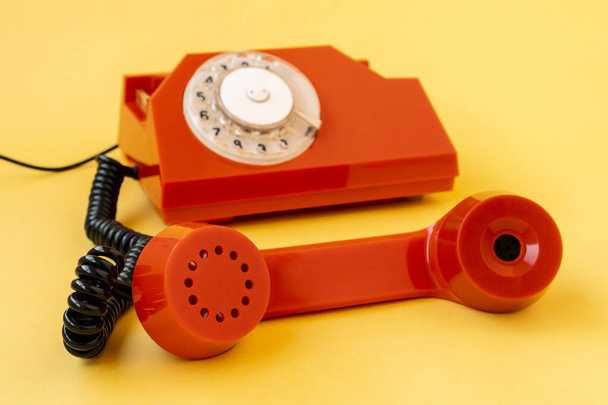 Retro orange telephone on yellow background, focus is on the handset - Foto, Imagem