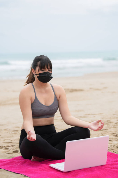 Mujer joven meditando con un portátil en la playa - Foto, imagen