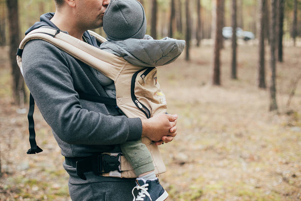 Concept de loisirs en plein air, séjour, santé mentale. Père portant son bébé garçon de 1 ans dans un sac ergo. - Photo, image