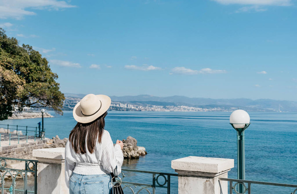 Rear view of female tourist standing on shore of sea in Opatija, Croatia. - Foto, Imagem