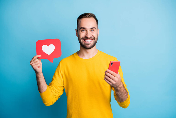 Photo portrait of student showing heart icon social media feedback keeping cellphone isolated on vibrant blue color background - Фото, зображення