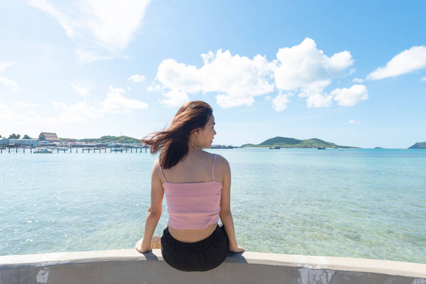 Zadní strana asijské ženy opálené kůže v růžové tílko a lícní straně. Dívá se do moře. Letní cestování. Relaxační, prázdninový a tropický relax koncept. - Fotografie, Obrázek