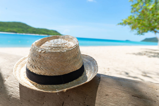 Stro hoed op het hout met strand en zee frisse lucht achtergrond. Vakantie en vakantie concept. Koelen en ontspannen concept. Verse feestdagen. Zomertijd. Kopieer ruimte voor bericht. - Foto, afbeelding