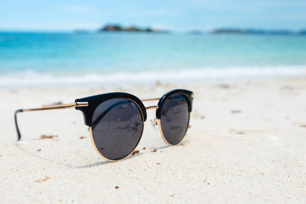 Černé sluneční brýle na mořském pozadí. krásná písečná pláž jako léto, Cestování a dovolená koncept. Koncept dovolené. Kopírovat místo pro zprávu. - Fotografie, Obrázek
