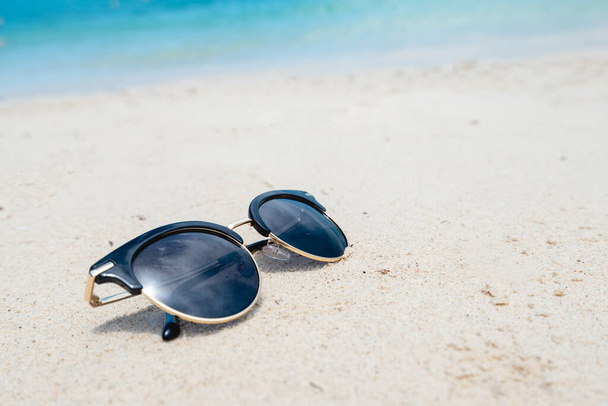 Gafas de sol negras sobre el fondo del mar. hermosa playa de arena como verano, Viajes y concepto de vacaciones. Concepto de vacaciones. Copiar espacio para el mensaje. - Foto, imagen