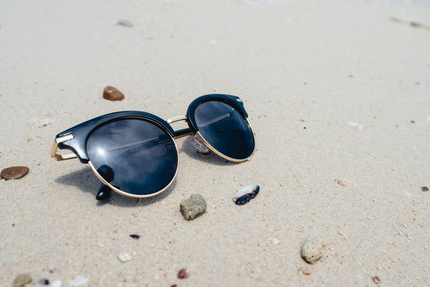 Fekete napszemüveg a tenger hátterében. gyönyörű homokos strand, mint a nyári, utazási és nyaralási koncepció. Ünnepi ötlet. Az üzenet másolási helye. - Fotó, kép