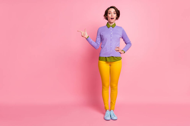 Full length photo of attractive lady direct finger empty space wear jumper pants sneakers isolated pink color background - 写真・画像