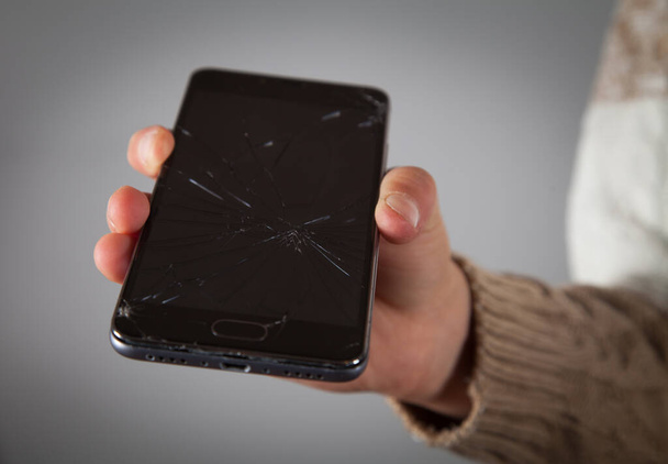 Broken phone in the hand of a caucasian boy. - Photo, Image