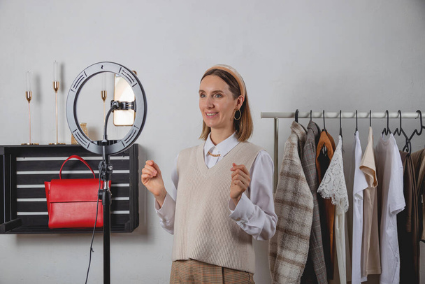 Mujer millennial estilista de moda graba vídeo de moda en smartphone con lámpara de anillo - Foto, Imagen