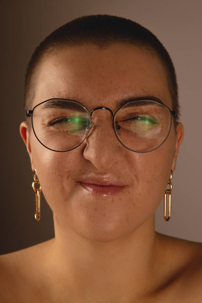 A swarthy girl with short hair and freckles in glasses grimaces and wrinkles the nose.  - Φωτογραφία, εικόνα