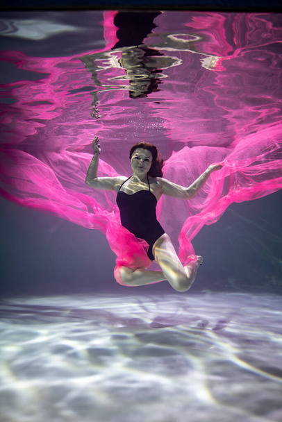 krásná dívka v černé plavky s červenou pareo na modrém pozadí pod vodou  - Fotografie, Obrázek