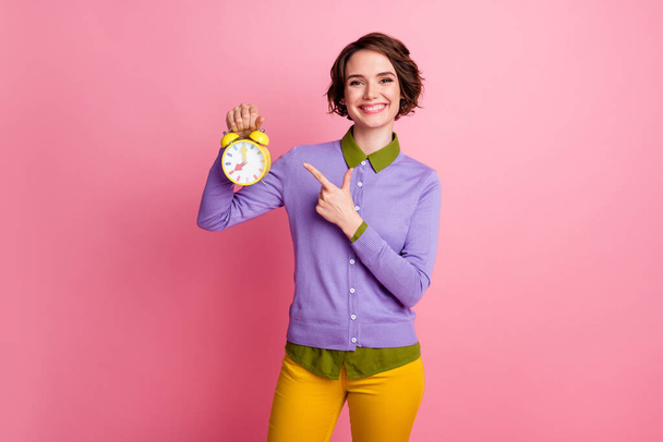 Photo of positive girl point index finger clock wear purple yellow pants trousers isolated pastel color background - 写真・画像