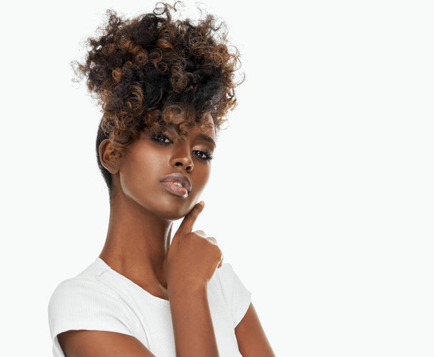 Portrait of attractive black woman touching cheek with afro hair isolated on white background - Foto, Imagem