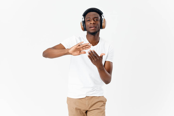 Afrikkalainen mies yllään kuulokkeet tinplate käsissä musiikki valo tausta - Valokuva, kuva